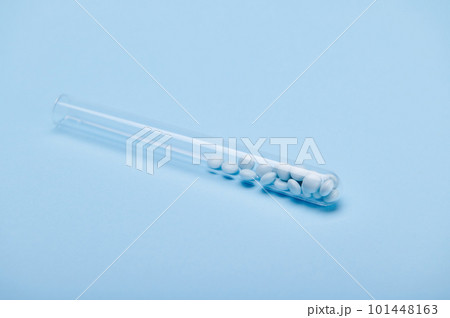 Medical blue colored pills in a laboratory test tube on isolated blue background. Prescription medicines. Healing dragees. Painkiller. Healthcare and medicine. Pharma business. Copy advertising space 101448163