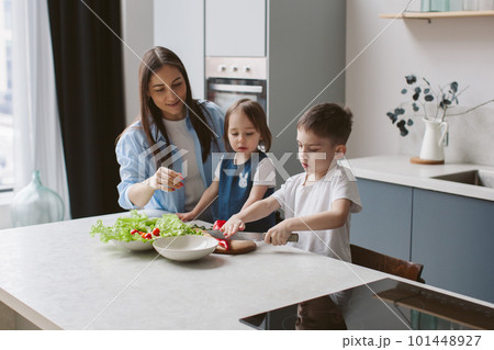 Mom teaches her six-year-old son how to cut a cucumber with a knife. Mom teaches her six-year-old son how to cut a cucumber with a knife. 101448927