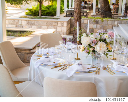 Wedding banquet concept. Chairs and round table for guests, served with cutler and, flowers and crockery and covered with a tablecloth 101451167