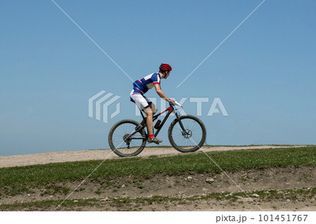 athlete cyclist riding mountain bike on hill in background blue sky, cross-country cycling 101451767