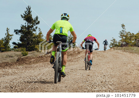 rear view group athlete cyclist riding mountain bike uphill, biking on gravel road, cycling competition rear view group athlete cyclist riding mountain bike uphill, biking on gravel road, cycling competition 101451779