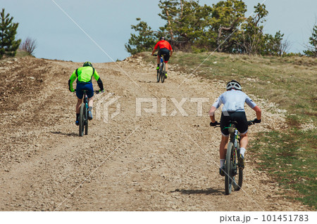 rear view three mountainbikers riding bike uphill, biking on gravel road, cycling competition rear view three mountainbikers riding bike uphill, biking on gravel road, cycling competition 101451783