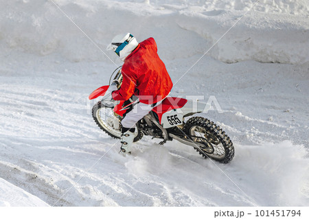 motocross rider riding sharp turn winter motorcycle racing, snow splashes from under rear wheel 101451794