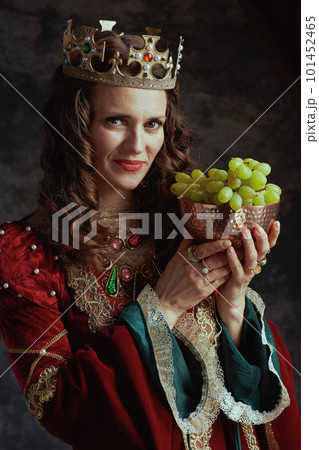 happy medieval queen in red dress with plate of grapes 101452465