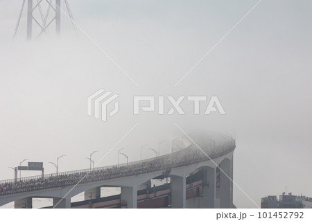 Running marathon - a crowd of people running on the bridge in a thick white fog 101452792