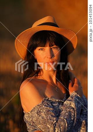 A young black-haired girl in a straw hat on a field with a bare shoulder 101453094