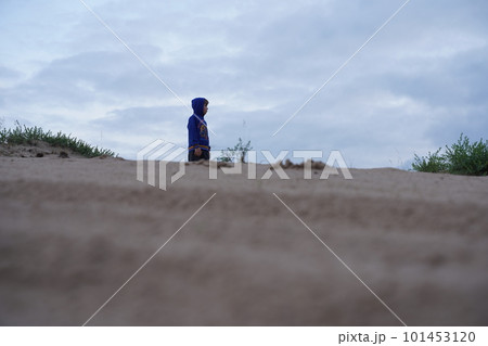 A lonely boy in the desert against the sky, viewed from below from afar. Selective focus 101453120