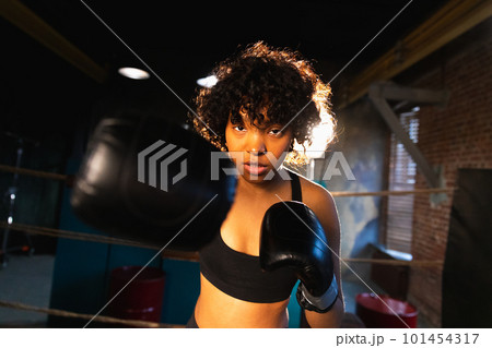 Women self defense girl power. African american woman fighter punching with boxing gloves to camera. Healthy strong girl punching training punches looking concentrated straight. Fit body workout 101454317