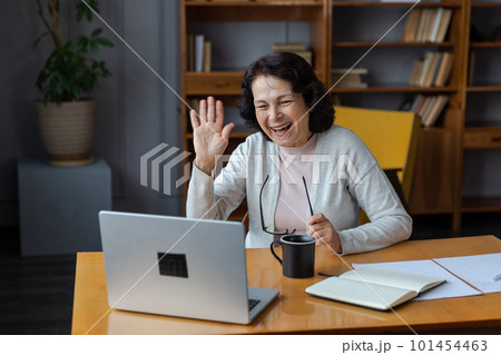 Happy middle aged senior woman sit with laptop talk on video call with friends family. Laughing mature old senior grandmother having fun talking speaking with grown up children online 101454463