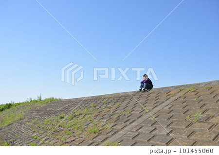 河川敷、土手の上で物思いにふける中学生の写真素材 [101455060] - PIXTA