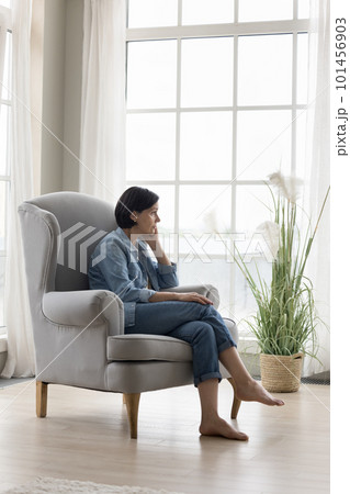 Serious thoughtful lonely mature lady sitting in armchair at home 101456903
