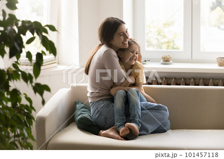 Joyful mom cuddling sweet little girl on home sofa Joyful mom cuddling sweet little girl on home sofa 101457118