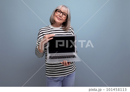 pleasant smiling middle aged 60s woman showing mockup web page on laptop on bright studio background pleasant smiling middle aged 60s woman showing mockup web page on laptop on bright studio background 101458113