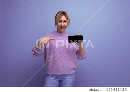 joyful cute blond woman in lavender sweater with smartphone mocap on purple background with copy joyful cute blond woman in lavender sweater with smartphone mocap on purple background with copy 101458126