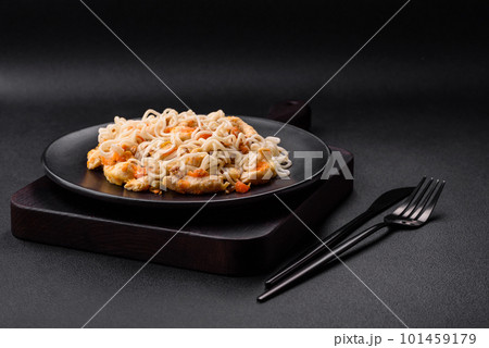 Delicious noodles with chicken and vegetables or udon on a black ceramic plate Delicious noodles with chicken and vegetables or udon on a black ceramic plate 101459179