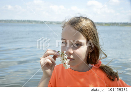 beautiful girl with a flower of a white acacia on the background of the blue sea 101459381