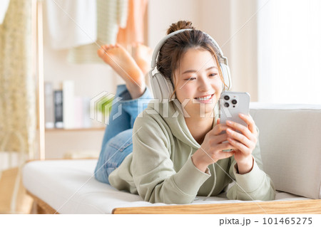 リビングでスマホを見る若い女性　 101465275