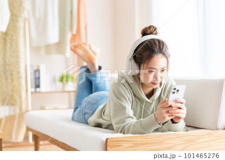 リビングでスマホを見る若い女性　 101465276