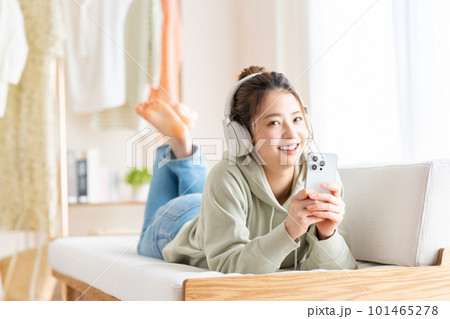 リビングでスマホを見る若い女性　 101465278