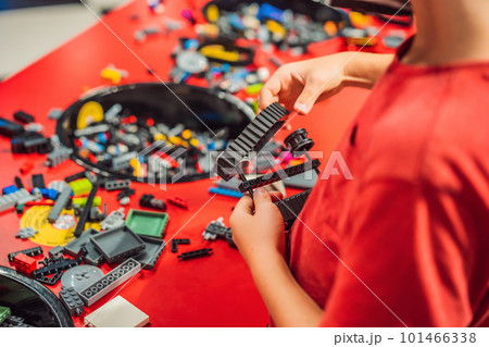 A boy in a medical mask plays with a constructor. child playing and building with colorful plastic bricks table. Early learning and development 101466338