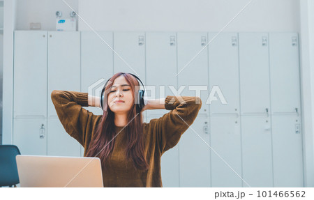 young student wearing headphones is relaxing during long online classes, distance learning, and keeps up to date on the global coronavirus pandemic. young student wearing headphones is relaxing during long online classes, distance learning, and keeps up to date on the global coronavirus pandemic. 101466562