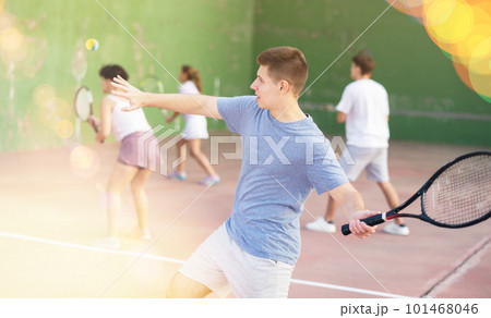 Young frontenis player swinging racquet to hit ball on outdoor court 101468046