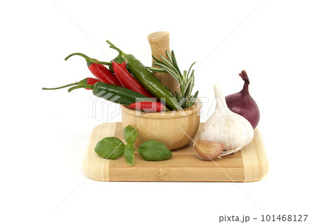 Chili peppers in wooden mortar and herbs over white 101468127