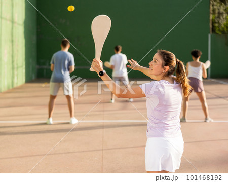 Portrait of sporty girl playing paleta fronton on outdoor court, ready to hit ball. Healthy and active lifestyle concept Portrait of sporty girl playing paleta fronton on outdoor court, ready to hit ball. Healthy and active lifestyle concept 101468192