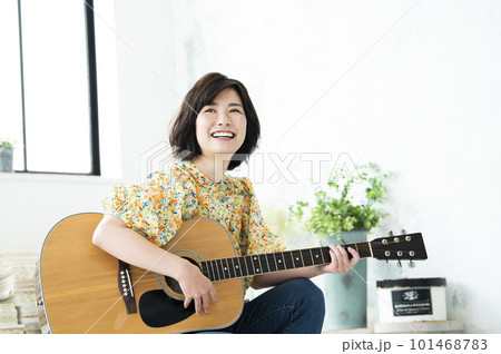 笑顔でギターを弾く若い女性 101468783