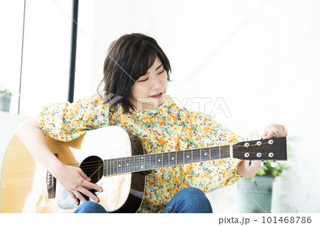 ギターのチューニングをする若い女性 101468786