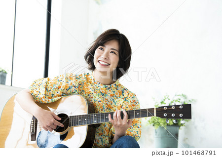 笑顔でギターを弾く若い女性 101468791