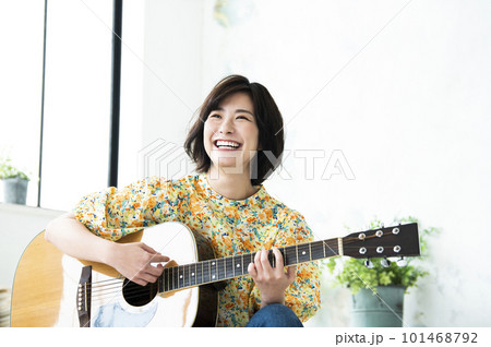 笑顔でギターを弾く若い女性 101468792