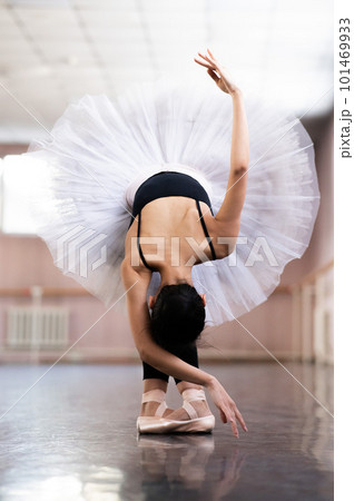 Graceful Asian ballerina in black bodysuit and white tutu poses in tilt.  101469933