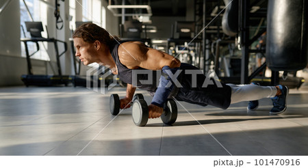Strong bodybuilder with muscular body doing push-up with dumbbells 101470916