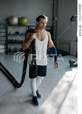 Young man with strong body shape carrying fitness ropes on shoulders 101470988