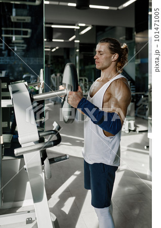 Athletic man wearing sportswear hanging weights on barbell bar Athletic man wearing sportswear hanging weights on barbell bar 101471005