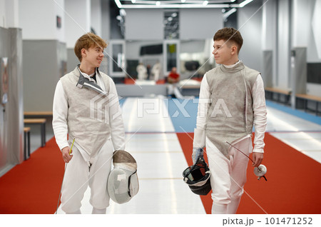 Two teenage student of swordsmanship school talking while going to dressing room Two teenage student of swordsmanship school talking while going to dressing room 101471252