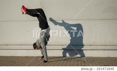 Caucasian man in hooded sweatshirt doing handstand outdoors.  101471840