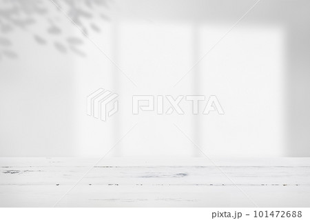 白い無垢のテーブルと窓から日差しが差し込んで木の葉の影が落ちている部屋。シンプルな背景素材。 101472688