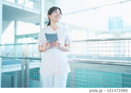 病院内でタブレットを操作するスクラブを着た女性医療従事者 病院内でタブレットを操作するスクラブを着た女性医療従事者 101472980