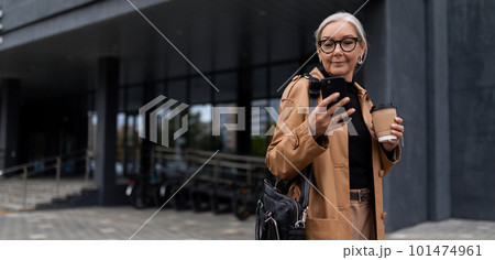 a mature adult female director with gray hair during a break with a phone stands against the 101474961