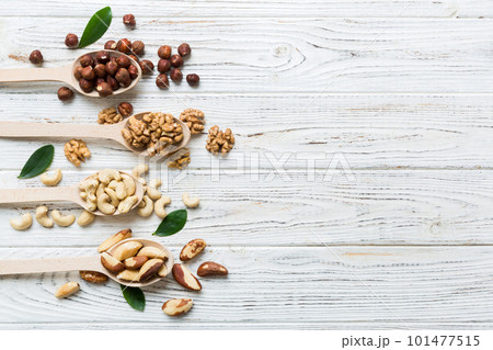 mixed nuts in white wooden spoon. Mix of various nuts on colored background. pistachios, cashews, walnuts, hazelnuts, peanuts and brazil nuts mixed nuts in white wooden spoon. Mix of various nuts on colored background. pistachios, cashews, walnuts, hazelnuts, peanuts and brazil nuts 101477515