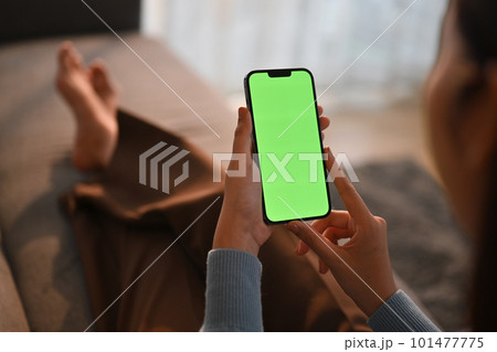 Woman using smart phone, relaxing on couch at home. Close up view, green screen for your advertising text message Woman using smart phone, relaxing on couch at home. Close up view, green screen for your advertising text message 101477775
