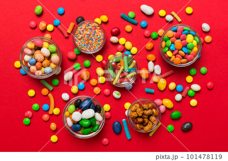 different colored round candy in bowl and jars. Top view of large variety sweets and candies with copy space different colored round candy in bowl and jars. Top view of large variety sweets and candies with copy space 101478119