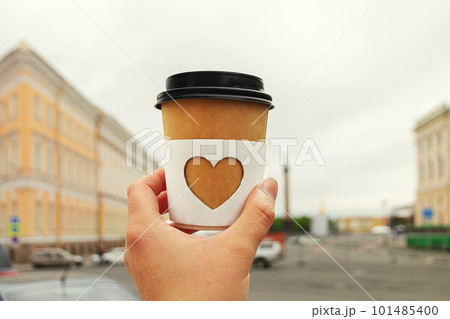 paper cup of natural coffee in women's hand against of center of St. Petersburg, Russia 101485400