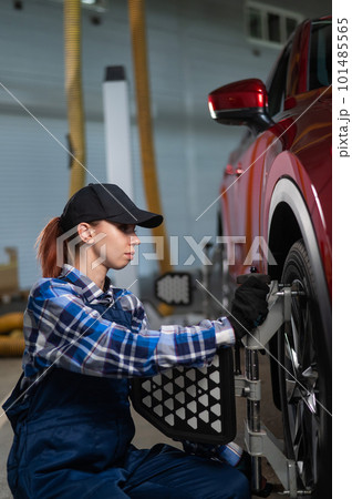 A female auto mechanic makes a camber. Woman working in a car service. 101485565