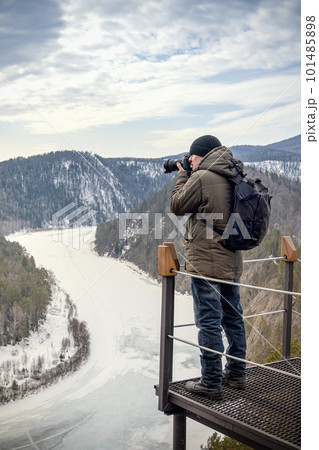 Travel photograph captures the frozen Mana River in the early springtime of Siberia's Mana Loop. The breathtaking view showcases the beauty of nature, with the river winding through the forest and 101485898