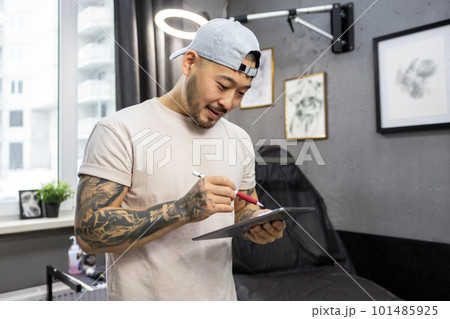 Young asian tattoo salon owner feeling good at his workplace Young asian tattoo salon owner feeling good at his workplace 101485925
