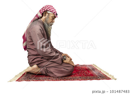 Muslim man with a beard wearing keffiyeh with agal in praying position (salat) on the prayer rug 101487483