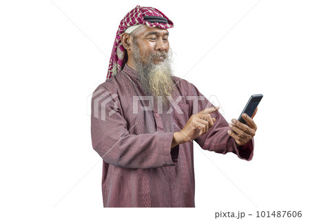Muslim man with a beard wearing keffiyeh with agal using mobile phone 101487606